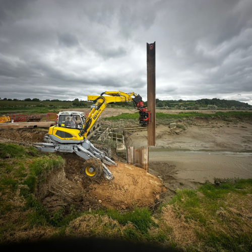 A movax driving piles into an embankment
